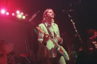 Kurt Cobain se apresentando ao vivo no palco com energia intensa, acompanhado por membros da banda, capturando a essência da música rock dos anos 90 e o espírito da expressão artística.