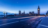 Vista ao crepúsculo das Casas do Parlamento e do Big Ben contra um horizonte urbano