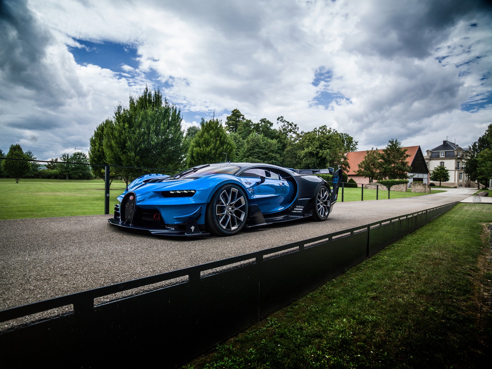 Um bugatti azul dirigindo-se por uma estrada em frente a uma casa (bugatti vision gran turismo, bugatti veyron, carro esportivo, supercarro, volkswagen)