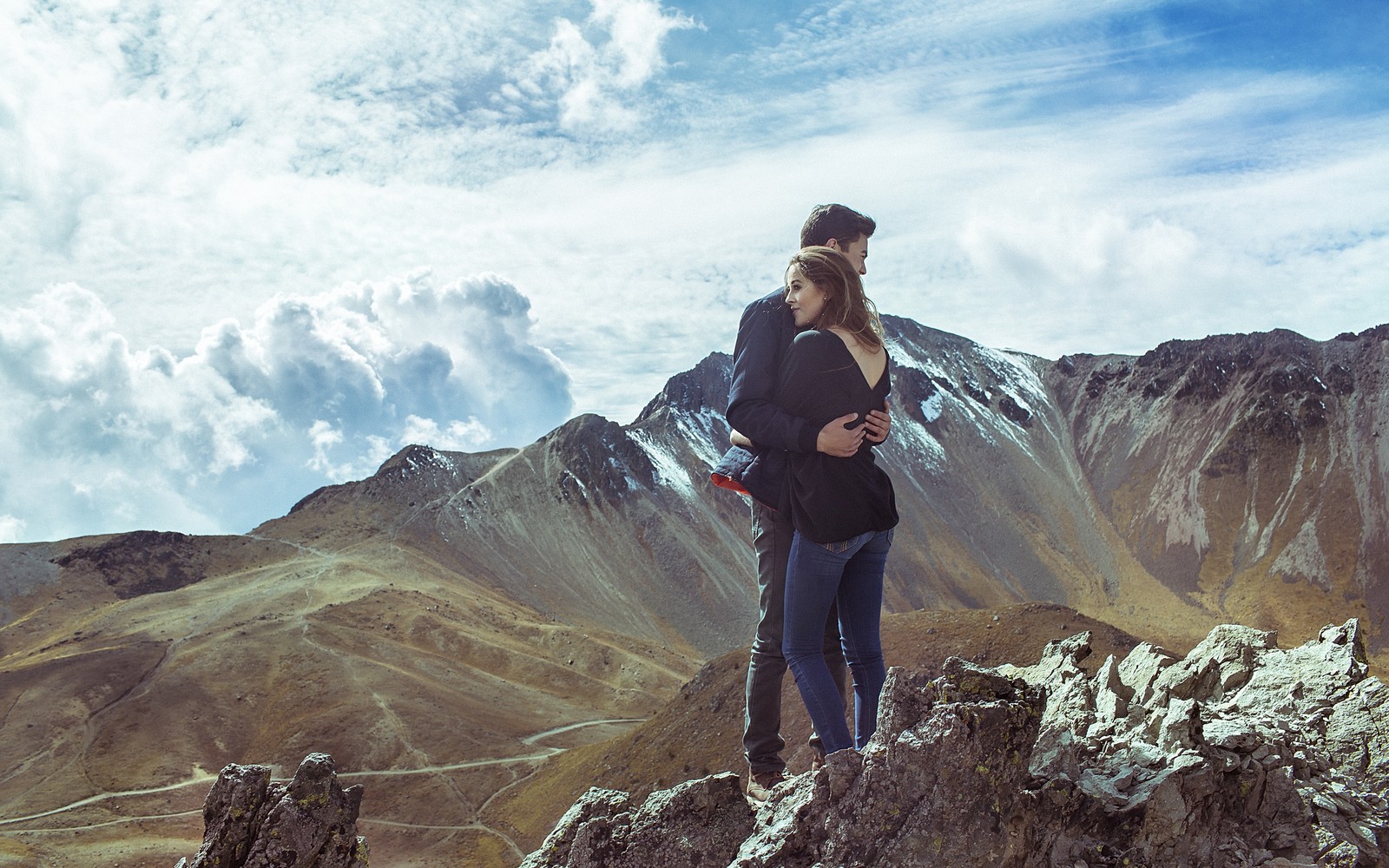 Une femme debout au sommet d'une montagne avec un appareil photo (formes montagneuses, sauvage, nuage, chaîne de montagnes, colline)