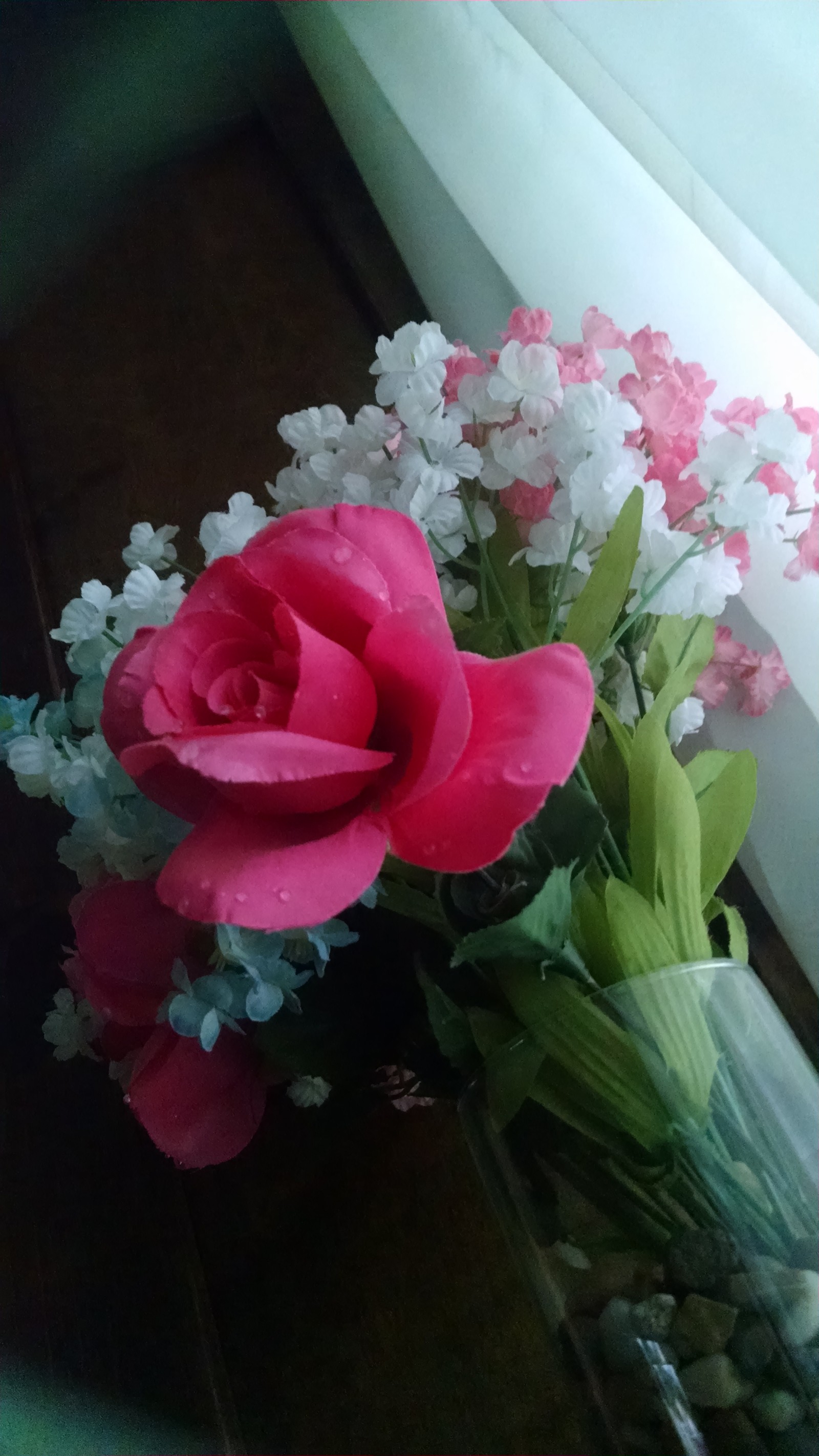 Há um vaso com uma rosa rosa e flores brancas dentro (engraçado, feliz aniversário)