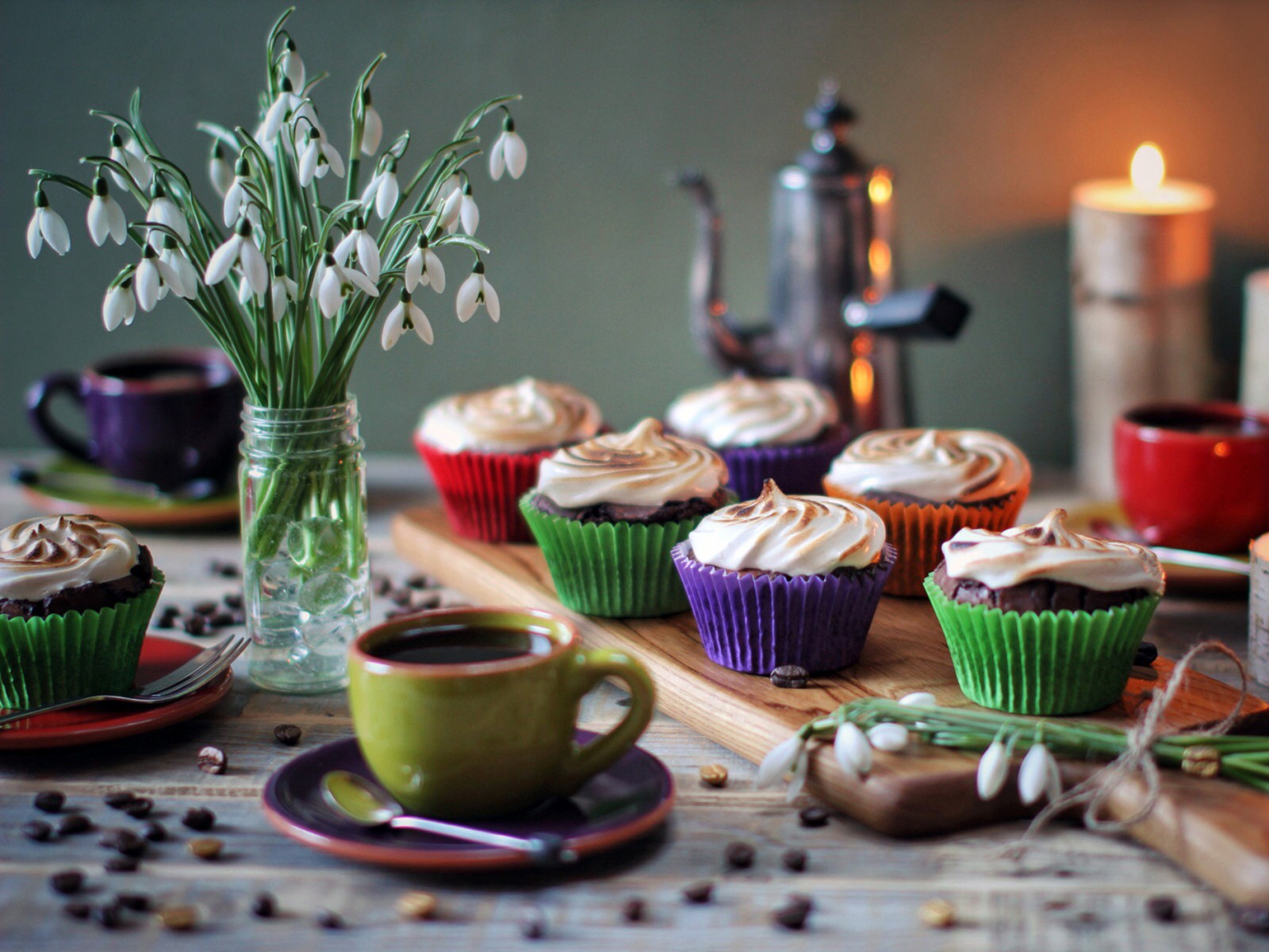 Hay cupcakes y café en una mesa con un jarrón de flores (taza, comida, dulzura, horneado, crema de mantequilla)