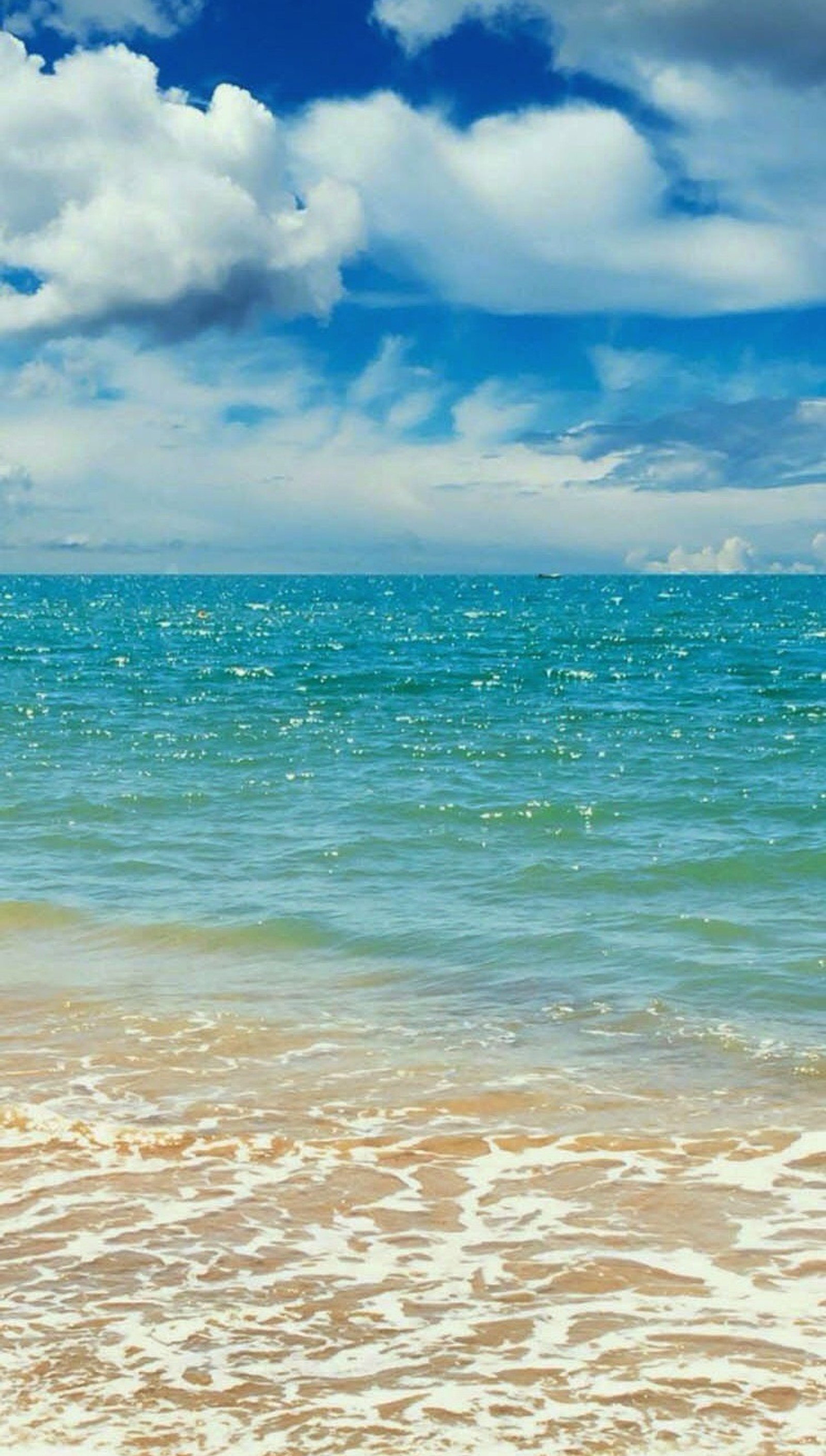 Un homme se tient sur la plage avec une planche de surf (eau bleue, nuages, océan, eau)