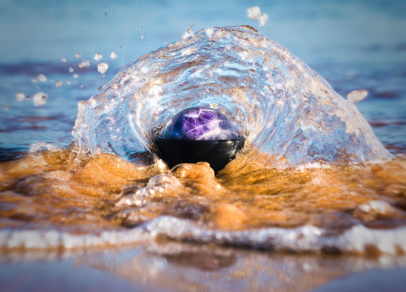 Un primer plano de una bola púrpura en el agua con una ola acercándose (agua, mar, ola, roca, océano)