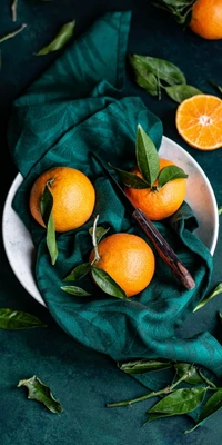 Fresh Oranges and Clementines on a Green Fabric with Leaves