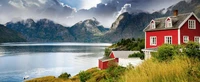 Charmantes rotes Haus an einem ruhigen Fjord, umgeben von majestätischen Bergen