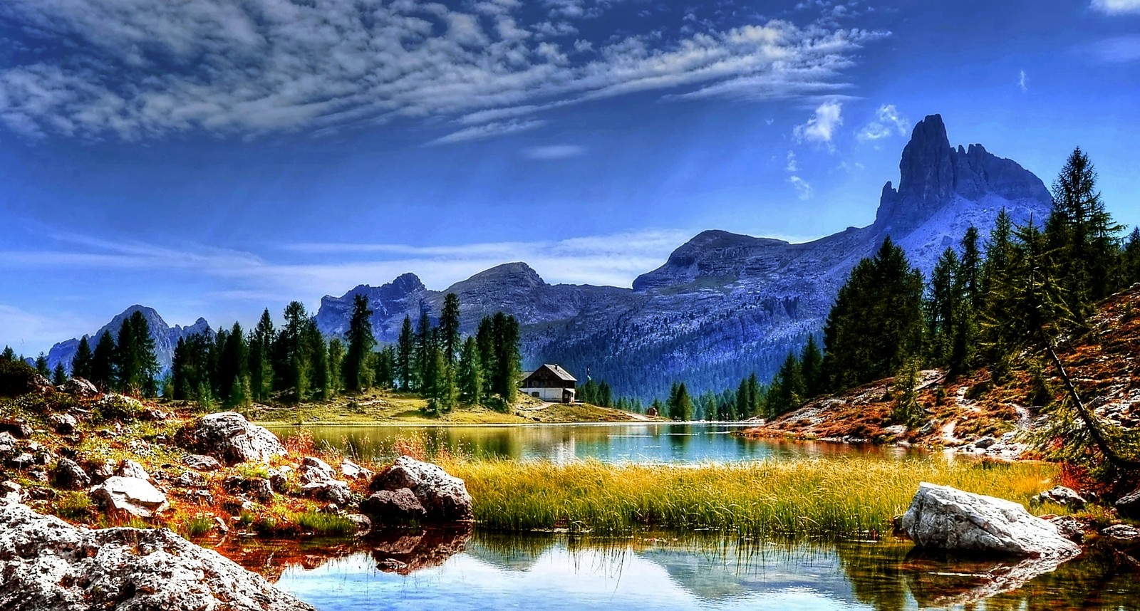 Vue panoramique d'une chaîne de montagnes avec un lac et une petite cabane au milieu (nature, montagne, formes montagneuses, sauvage, réflexion)