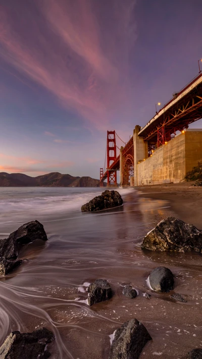 Pont du Golden Gate au crépuscule avec des eaux tranquilles et une côte rocheuse