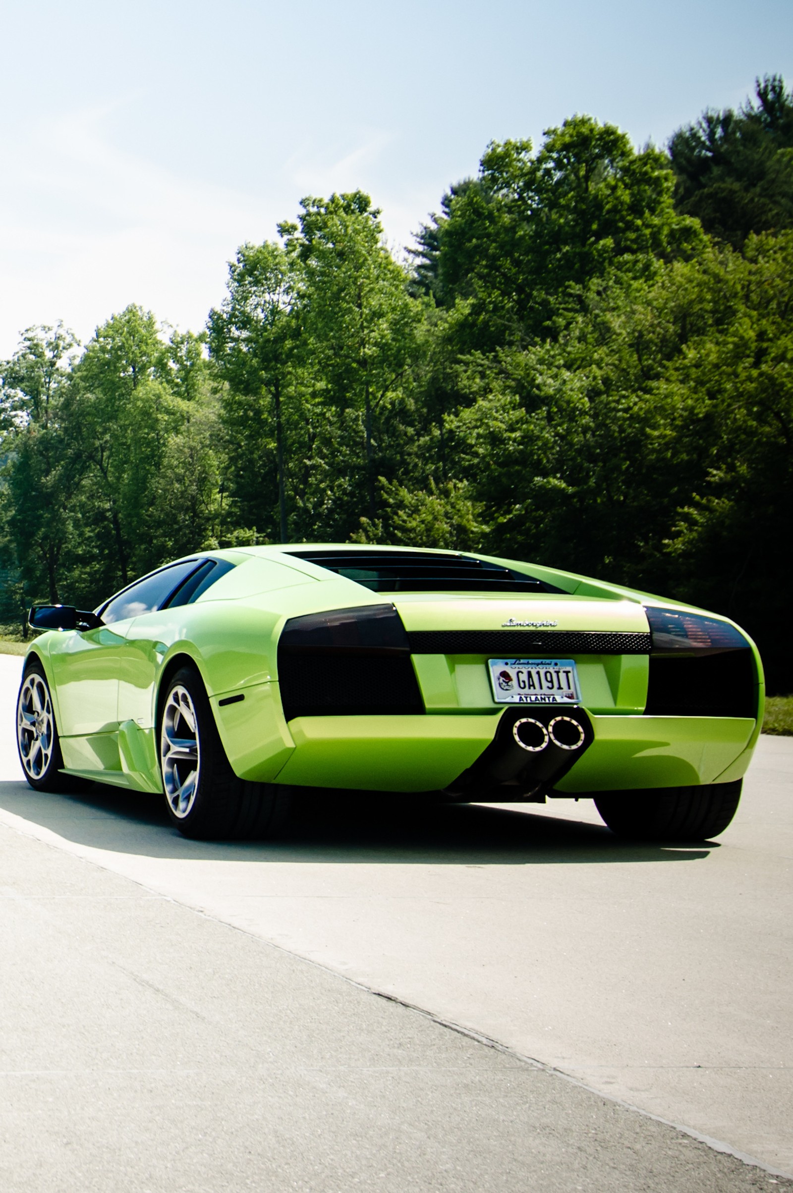 Arafed green sports car parked on a paved road next to trees (auto, car, italy, lamborghini, sport)