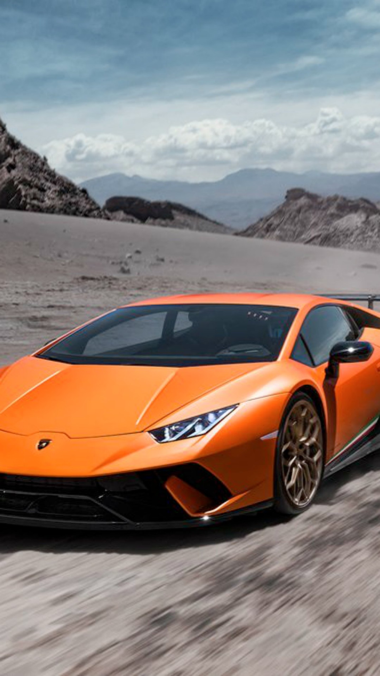 Близкий план оранжевого lamborghini, едущего по пустынной дороге (huracan, производительный)