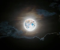 Silhouette of an Airplane Against a Full Moon and Clouds