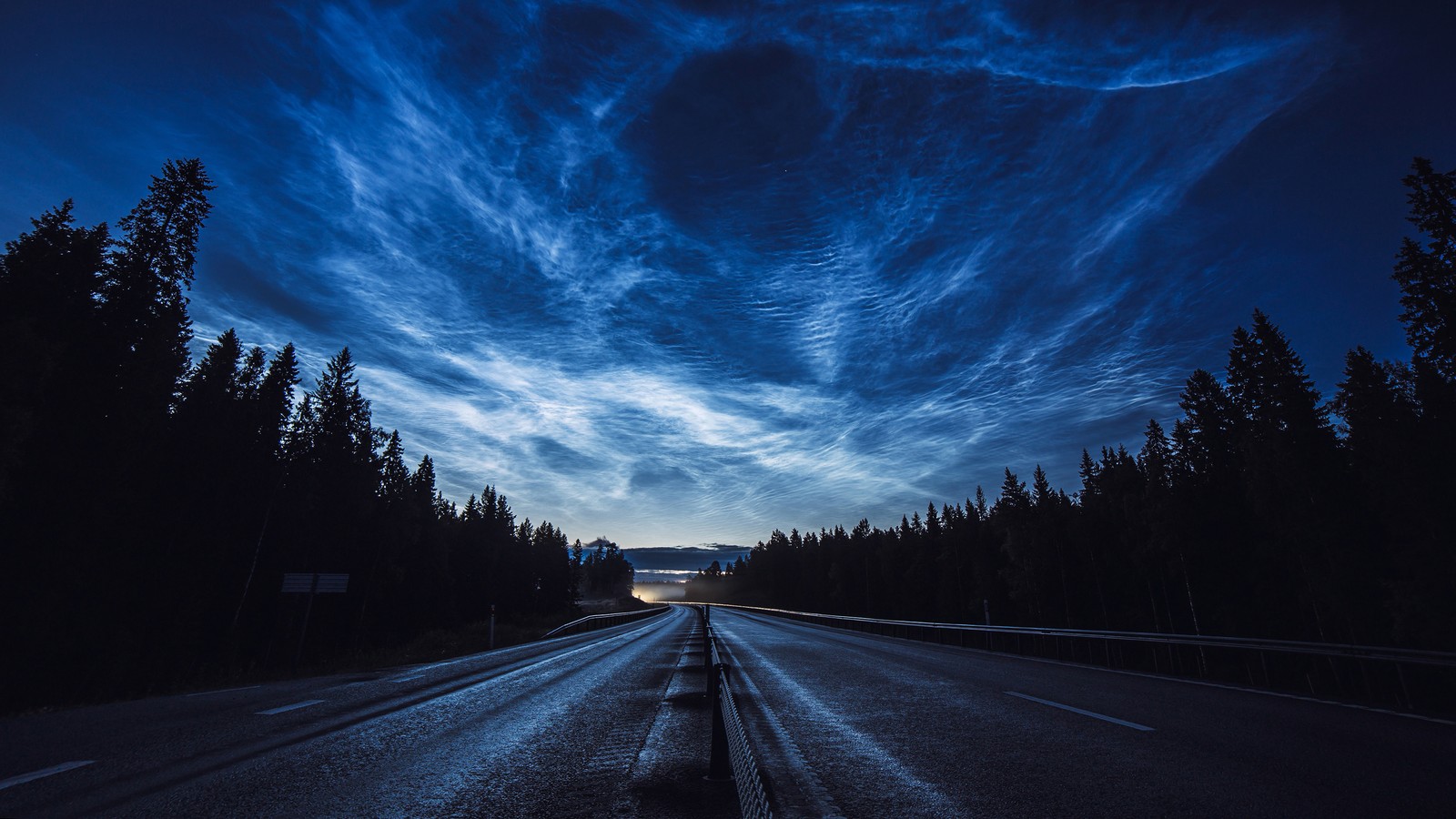 Arafed view of a highway with a truck driving on it at night (sky, clouds, scenery, road, forest)