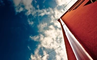 Cielo azul con nubes cúmulos sobre un edificio rojo