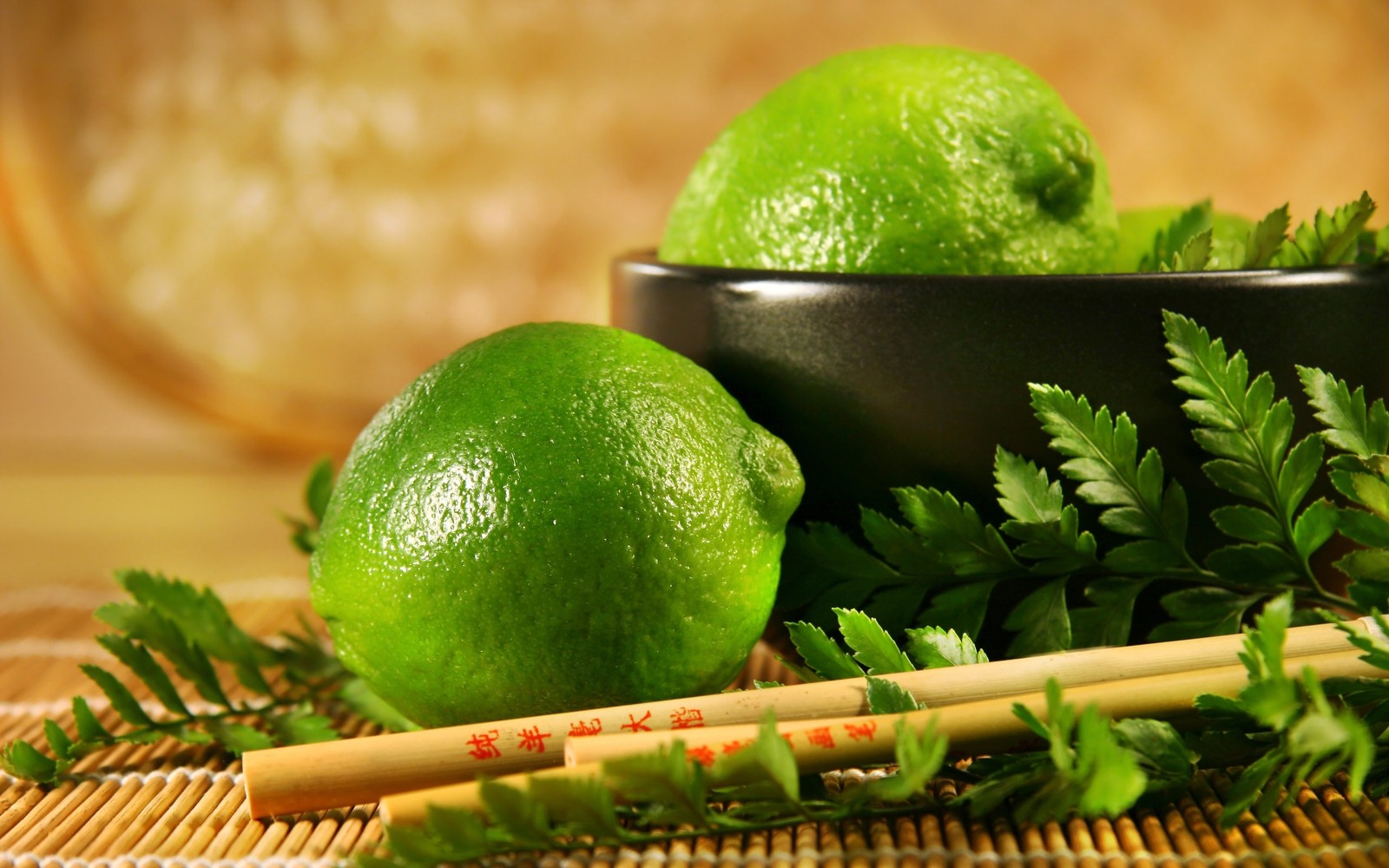 Hay dos limones y dos palillos en una mesa (lima clave, lima persa, cítricos, fruta, vegetal de hoja)