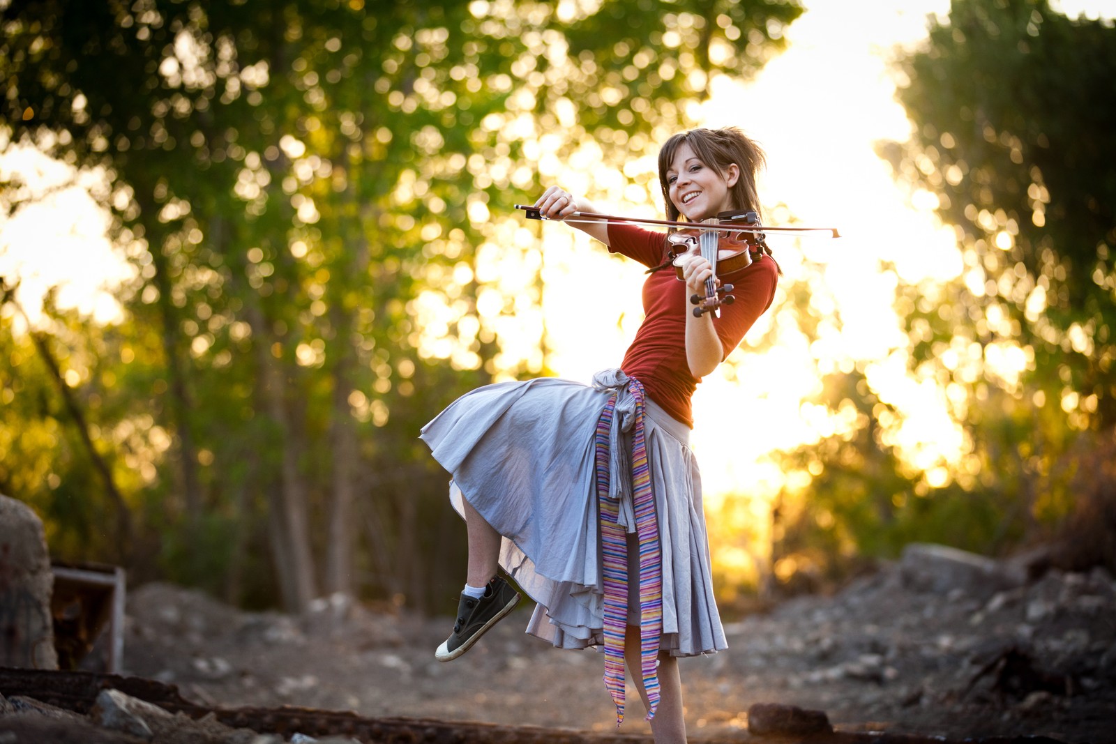 Una chica con falda tocando el violín en el bosque (violín, luz solar, árbol, diversión, niña)