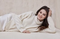 Selena Gomez relaxing in a cozy cream sweater, exuding warmth and charm.