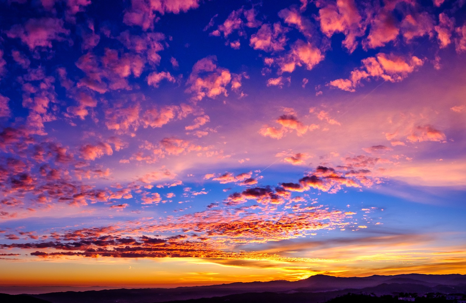 Une vue d'un coucher de soleil coloré avec des nuages et des montagnes en arrière-plan (heure dorée, 5k, coucher de soleil, nuages, paysage)