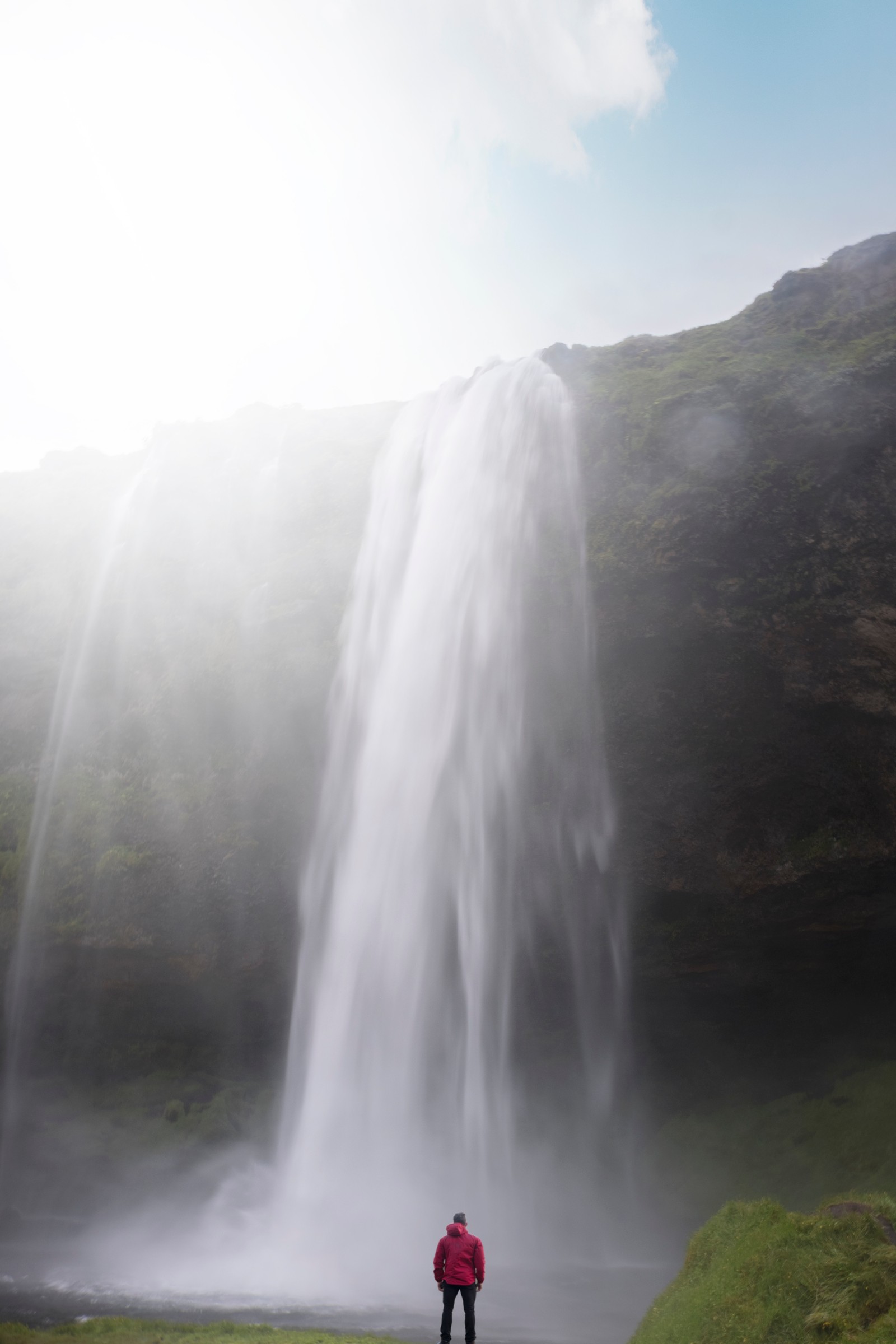 Homme arabe debout devant une cascade avec une veste rouge (la cascade, cours deau, ressources en eau, eau, hauts plateaux)