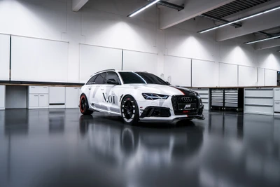 Audi RS6 personalizado con tuning ABT Sportsline, con un llamativo color blanco, llantas de aleación agresivas y un diseño elegante en un entorno de taller moderno.