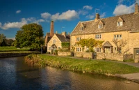 Charming riverside cottage with lush greenery and a tranquil waterway.