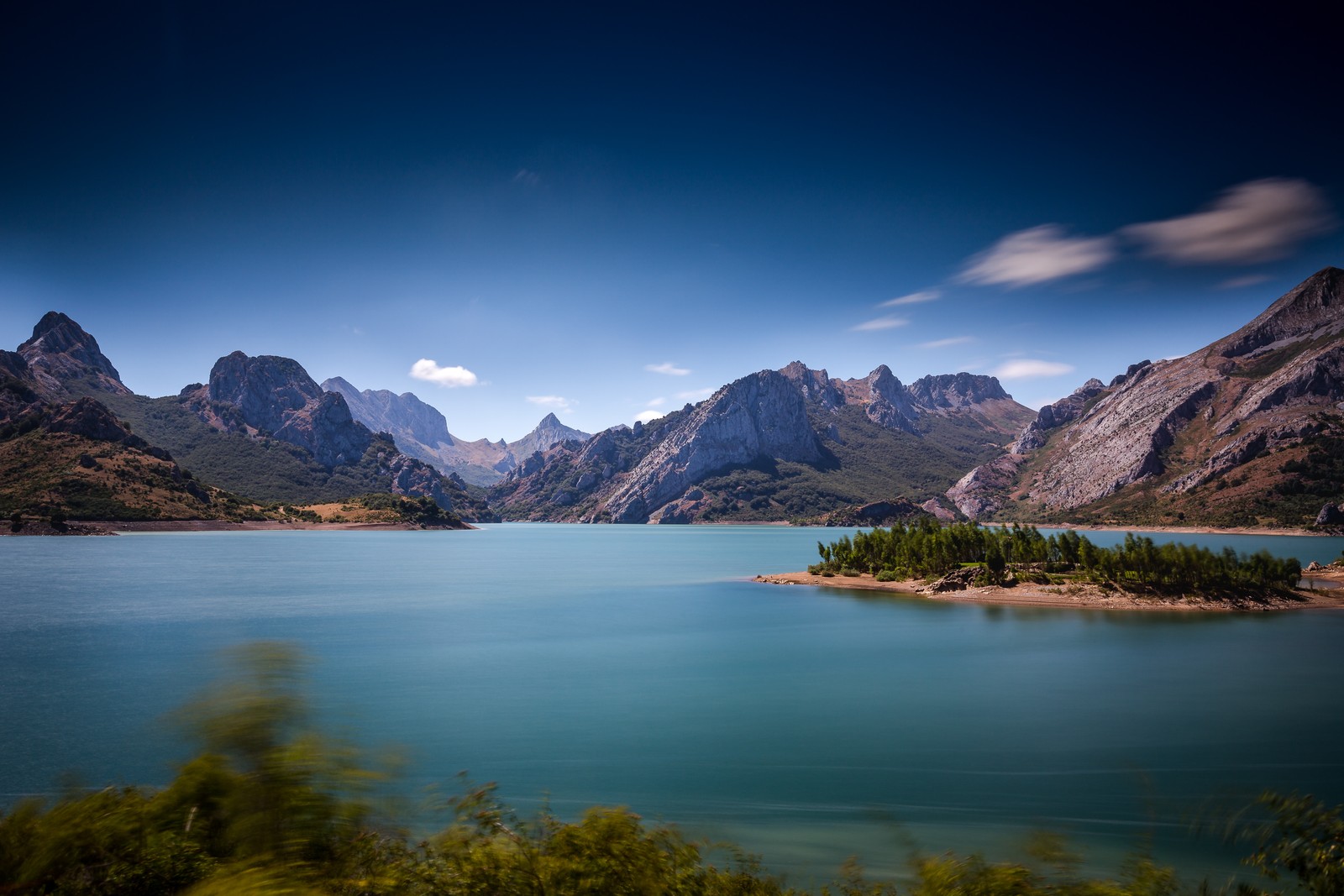 Vista distorsionada de un lago con montañas al fondo (picos de europa, españa, cordillera, cielo azul, paisaje)