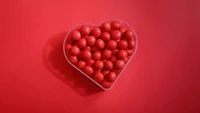 Heart-Shaped Container Filled with Red Sugar Candies on a Red Background