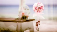 Delicate pink floral bouquet centerpiece for a wedding ceremony, elegantly displayed near a serene beach backdrop.