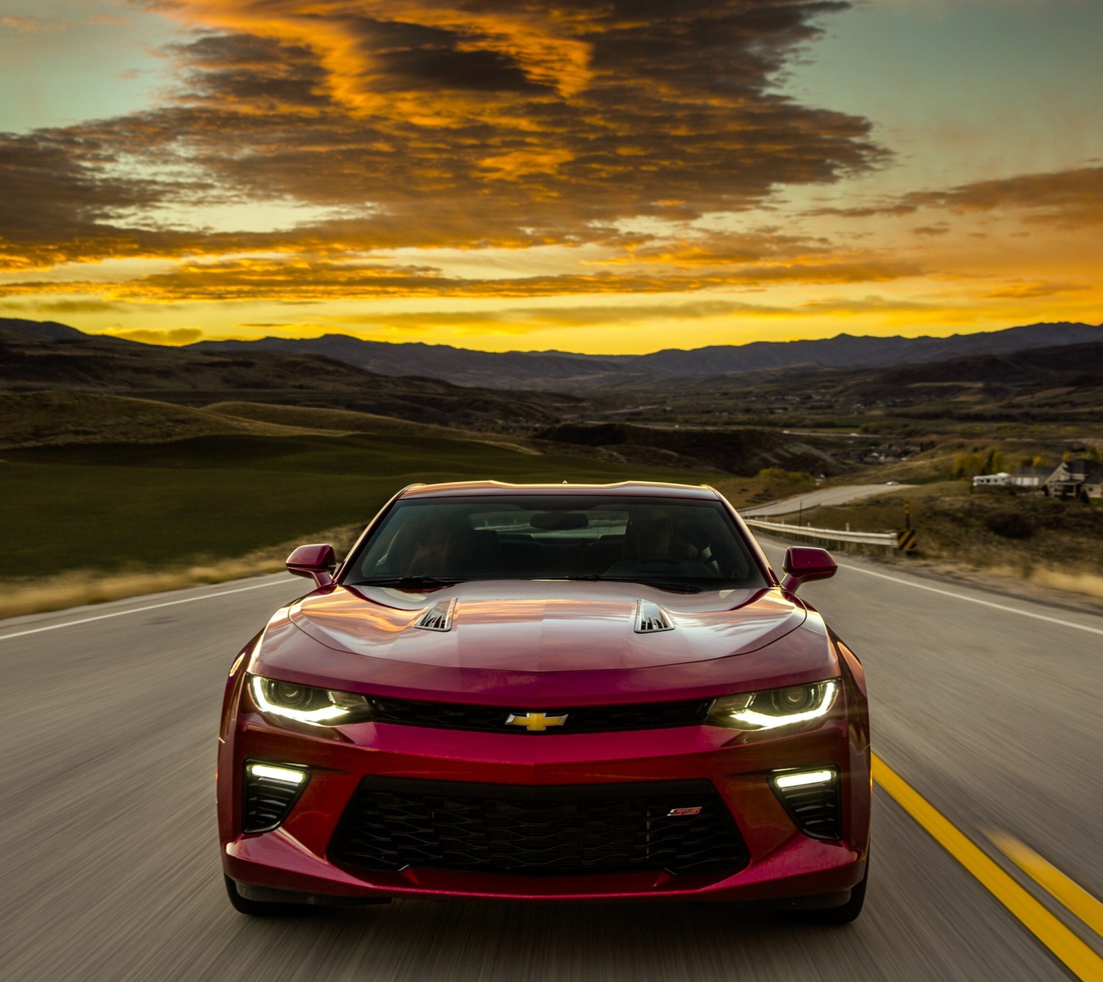 A red chevrolet camaro driving down a road at sunset (america, camaro, chevrolet, europe, muscle)