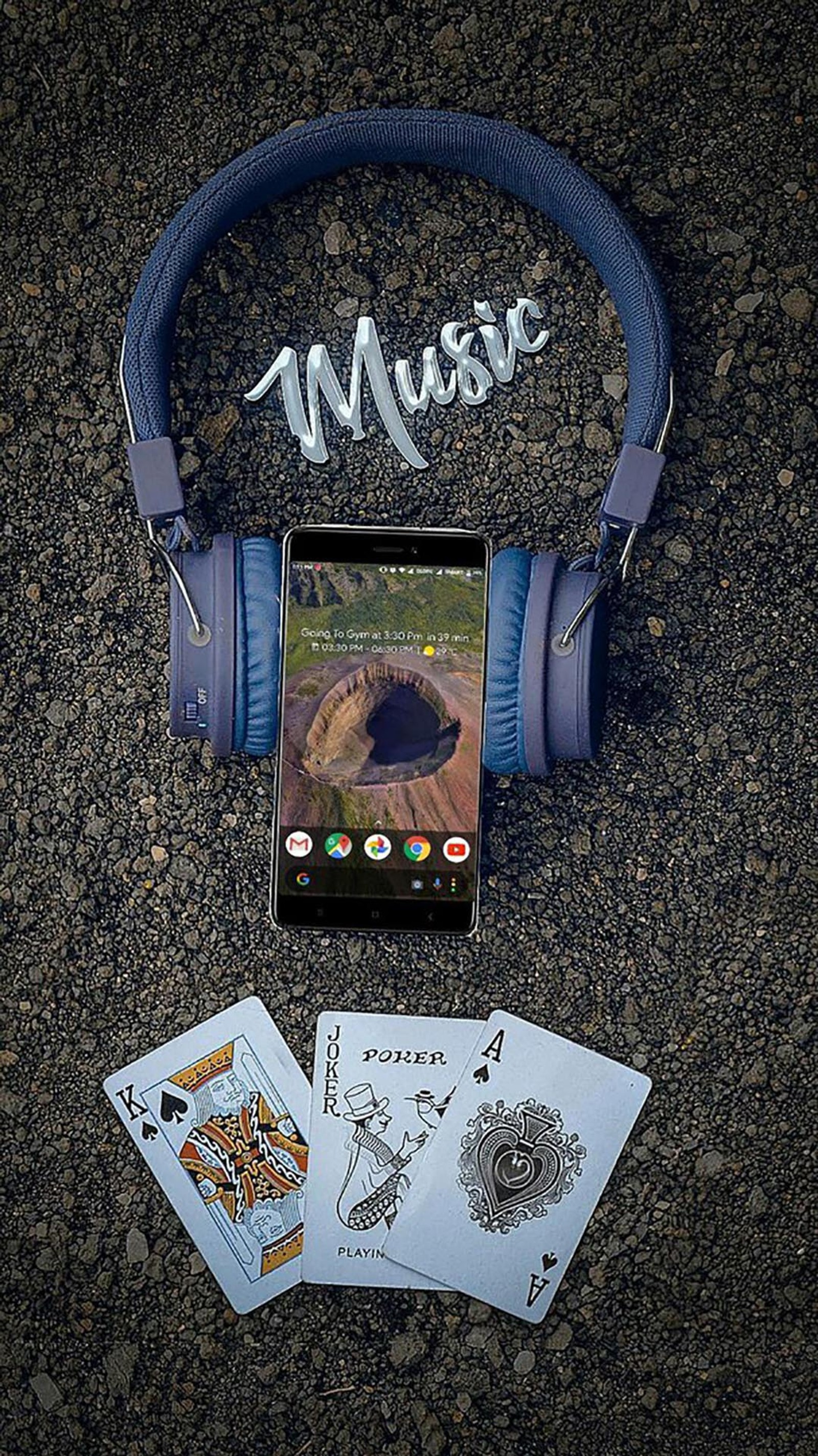 Uma imagem de um telefone celular com fones de ouvido e cartas de baralho (fantastica, música)