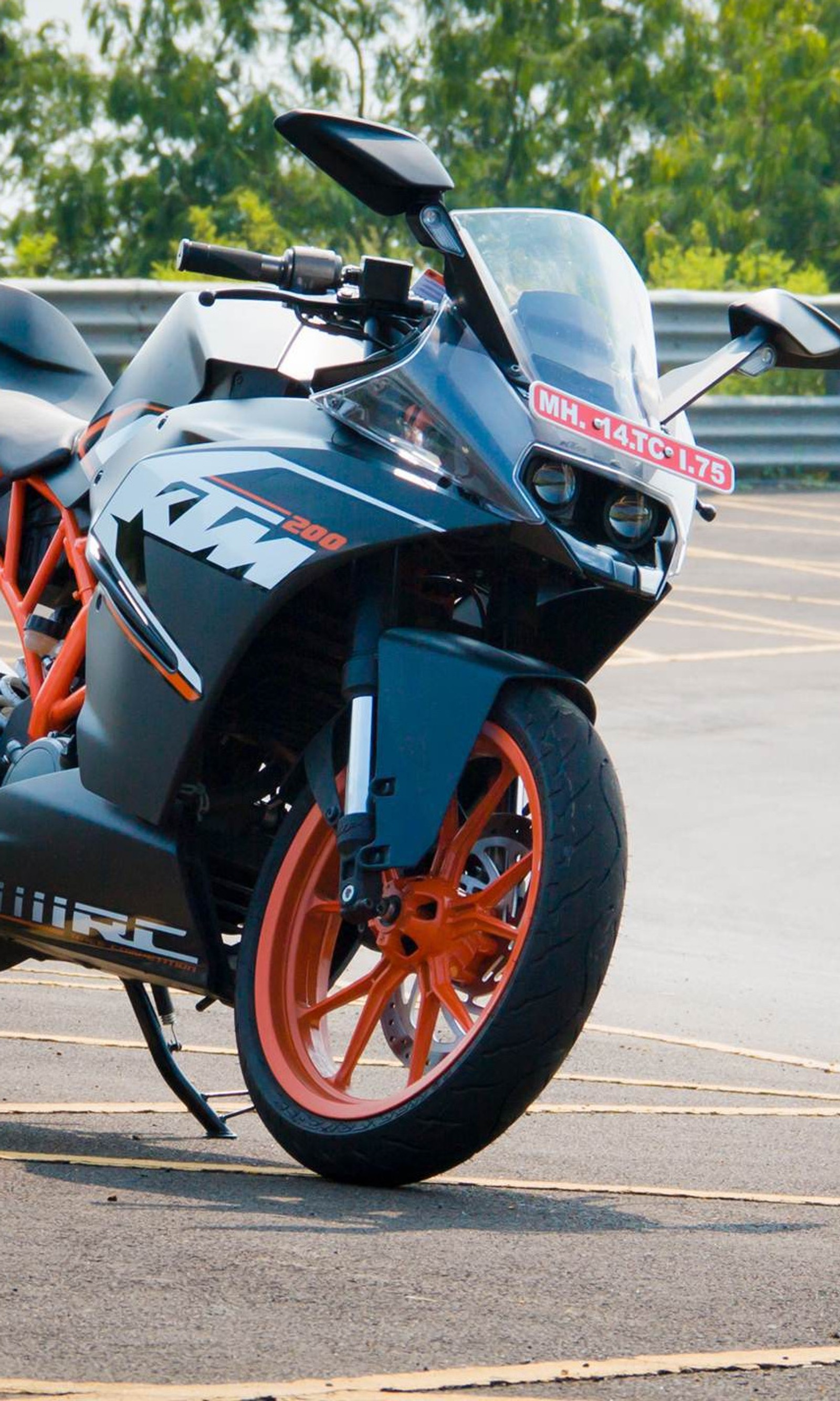 Hay una motocicleta estacionada en un estacionamiento con llantas naranjas (bicicleta, duque, ktm, carreras, velocidad)