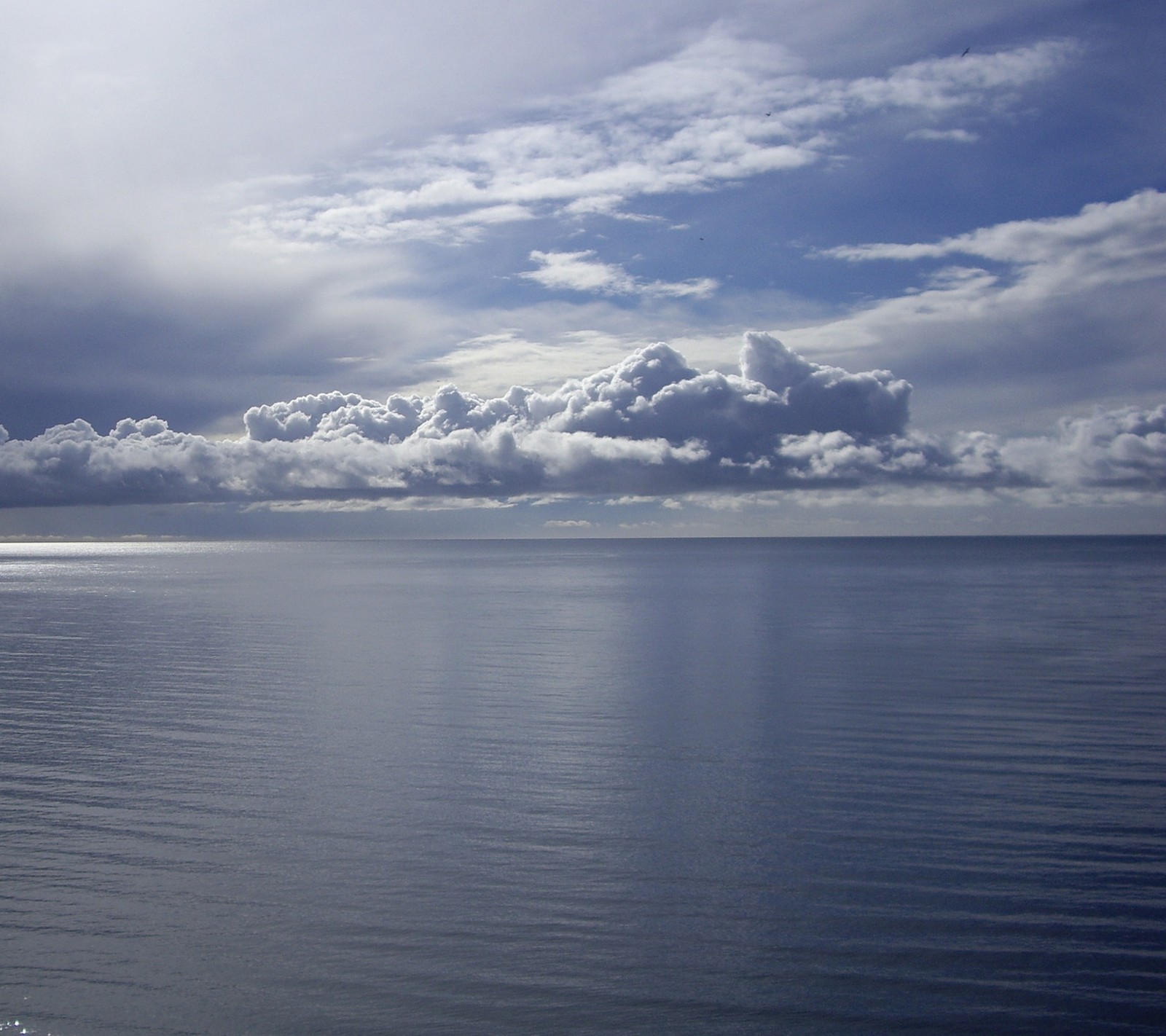 Il y a un bateau qui est sur l'eau sous un ciel nuageux (bleu, nuage, mer, ciel, eau)