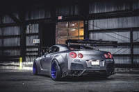 Nissan GTR gris mat avec accents bleus et aileron turbo dans un cadre industriel