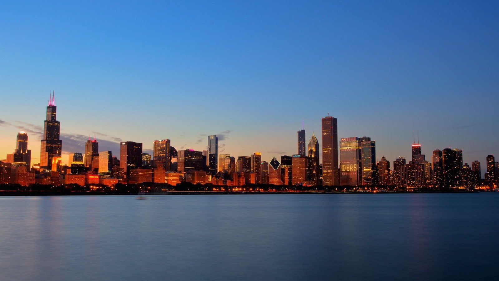 Uma visão árabe do horizonte da cidade ao cair da noite com um lago à frente (chicago, cidade, linha do horizonte, paisagem urbana, área urbana)