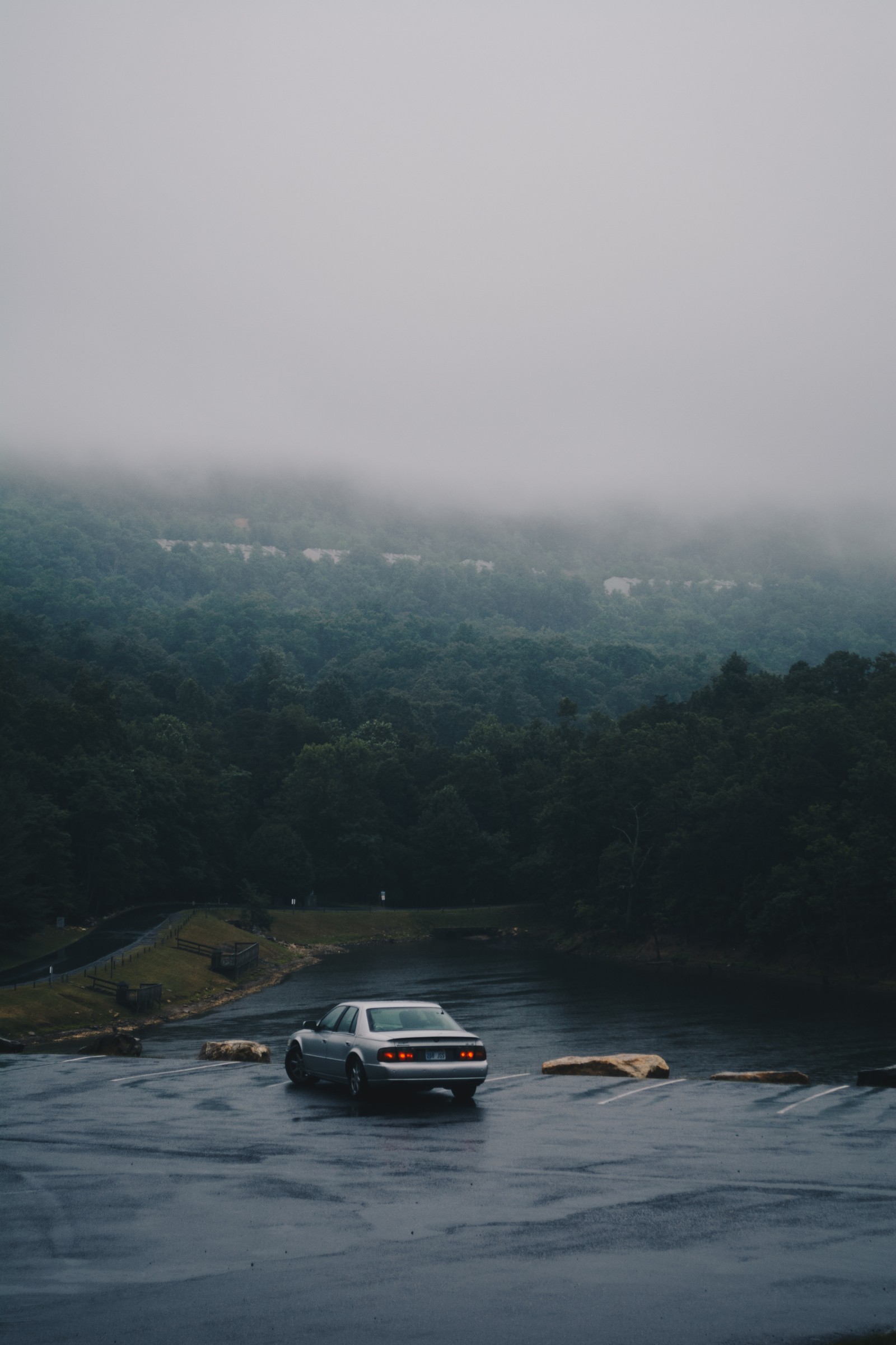 Ein auto, das im wasser neben einem hügel parkt (nebel, hochland, wolke, himmel, bergstation)