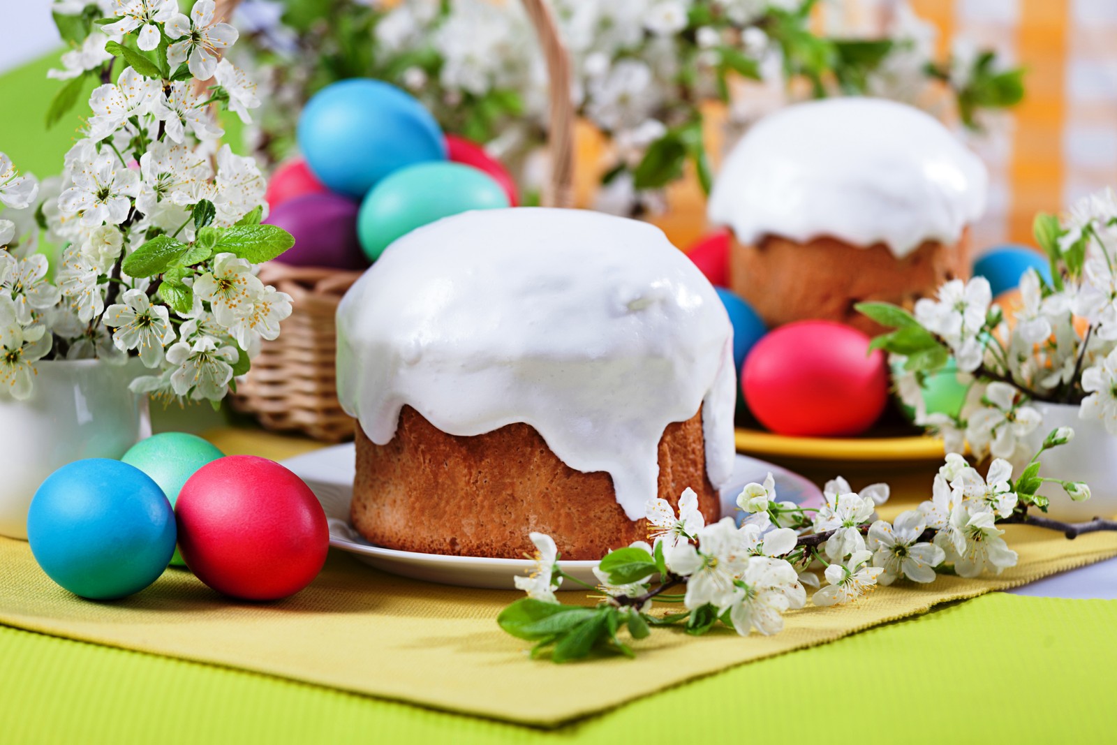 Hay un pastel con glaseado y huevos en una mesa (kulich, pascua, huevo de pascua, comida, plato)