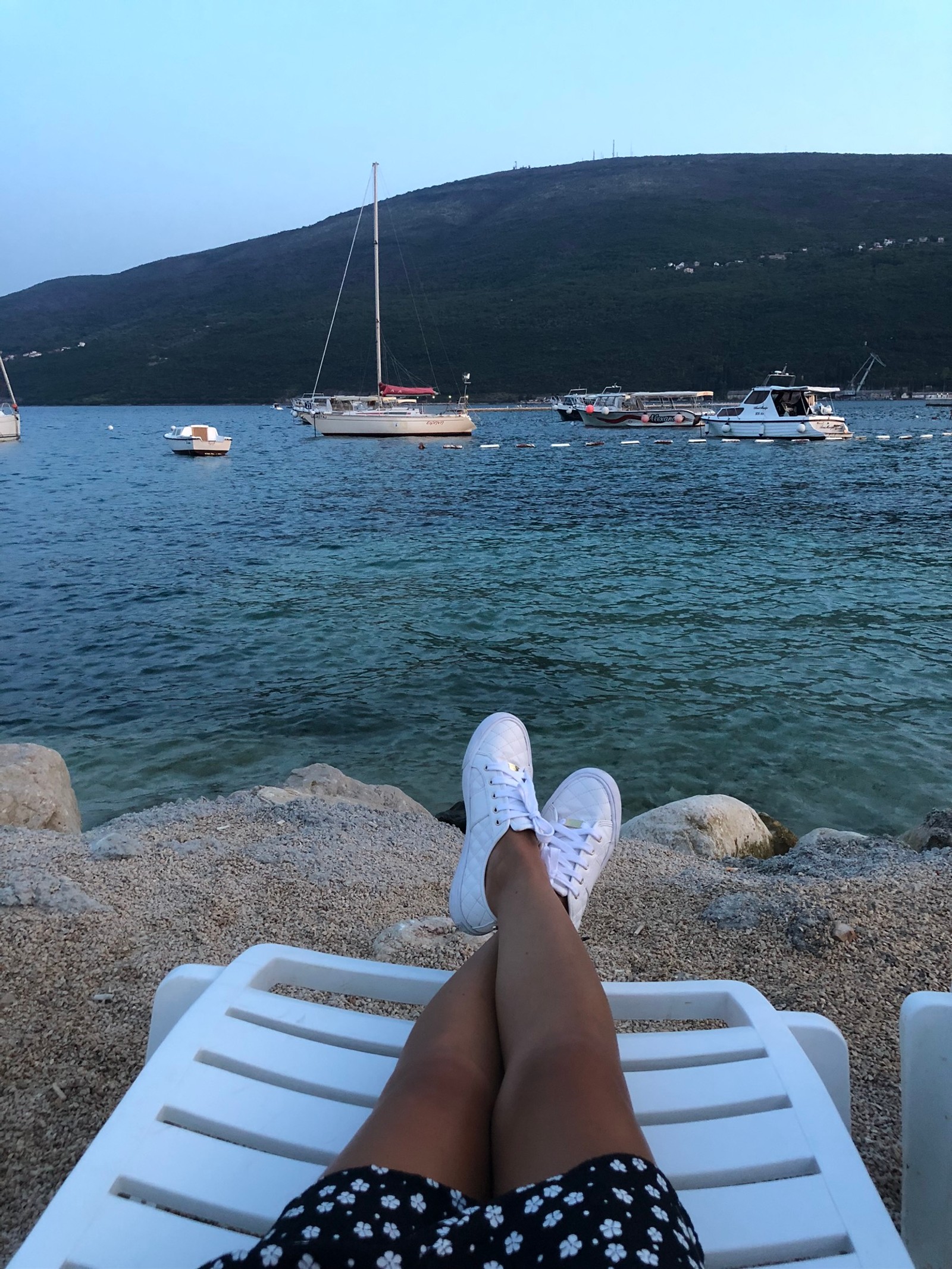 Someone is sitting on a chair on the beach with their feet up (sea, boat, tourism, water, beach)