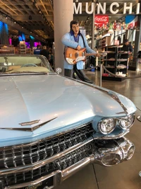 Cadillac azul clássico com estátua de Elvis no salão do automóvel