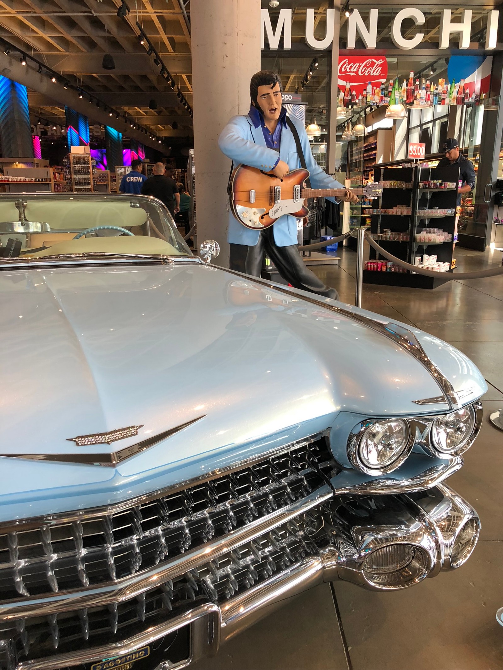 Hay un hombre tocando la guitarra frente a un coche (clásico, rey, coche mediano, salón del automóvil, capucha)