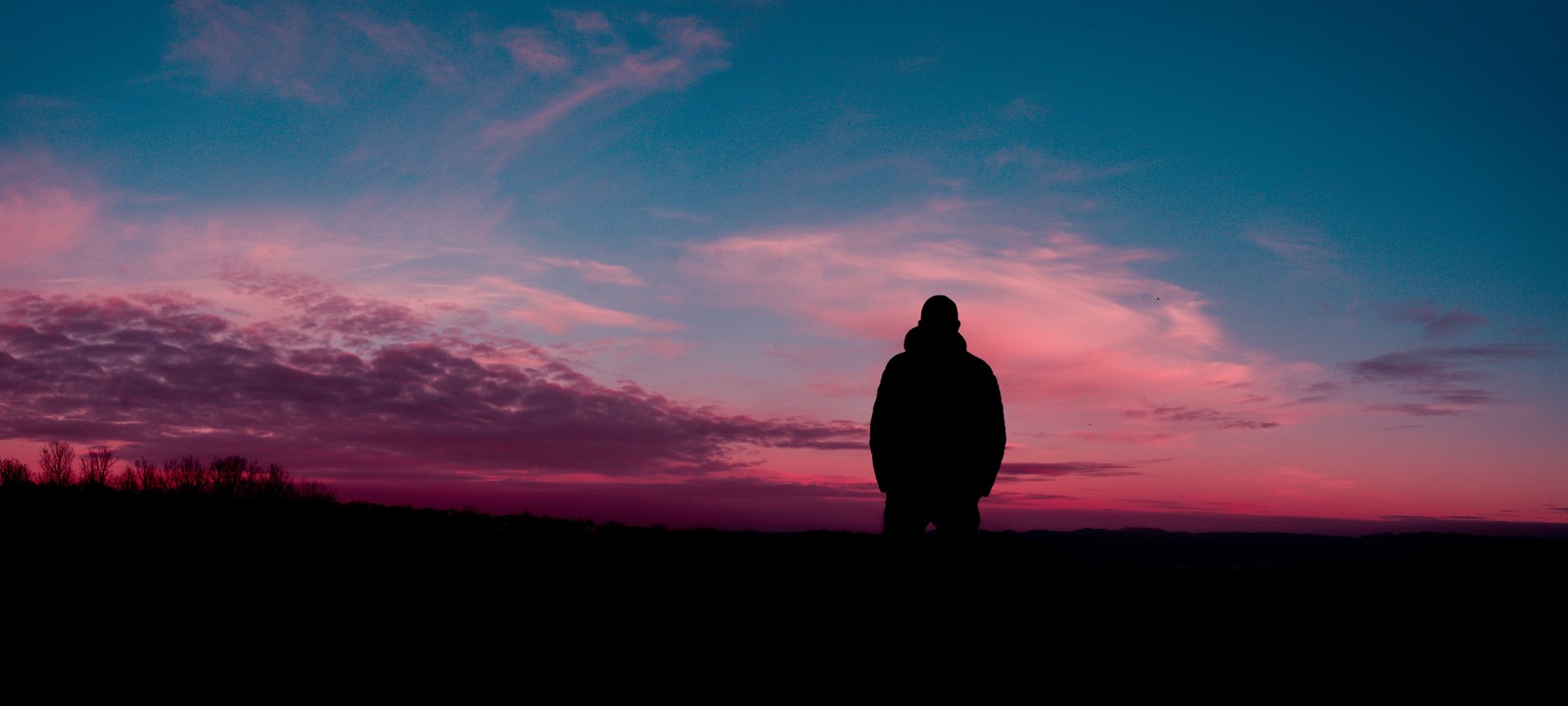 Silhouette d'une personne debout sur une colline au coucher du soleil (seul, amour)