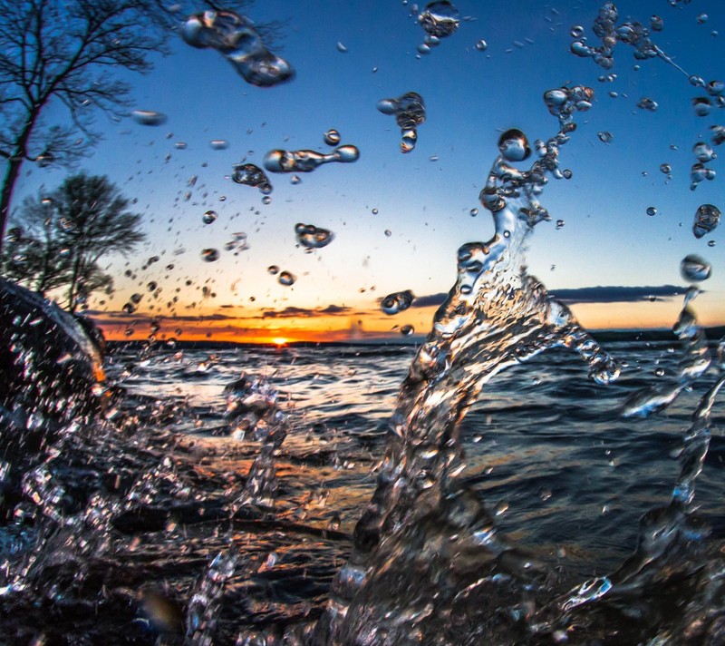 A close up of a wave hitting the shore of a lake (drops, ocean, sea, summer, water)