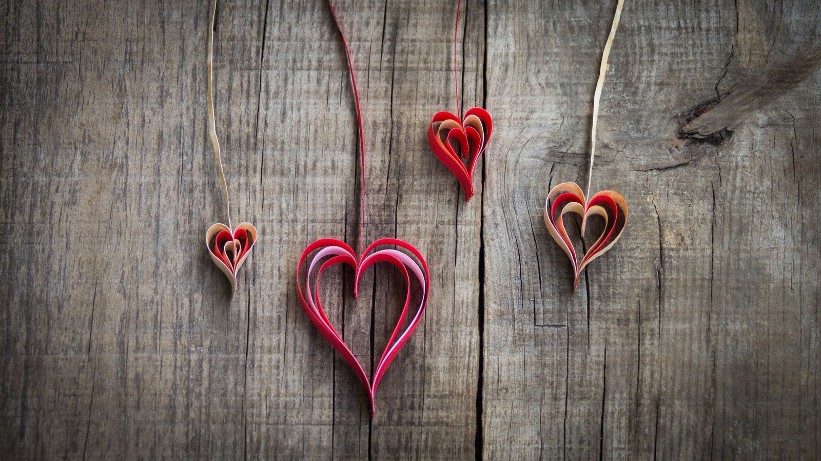 Tres corazones rojos colgando de un hilo sobre una superficie de madera (corazón, rojo, amor, día de san valentín, madera)