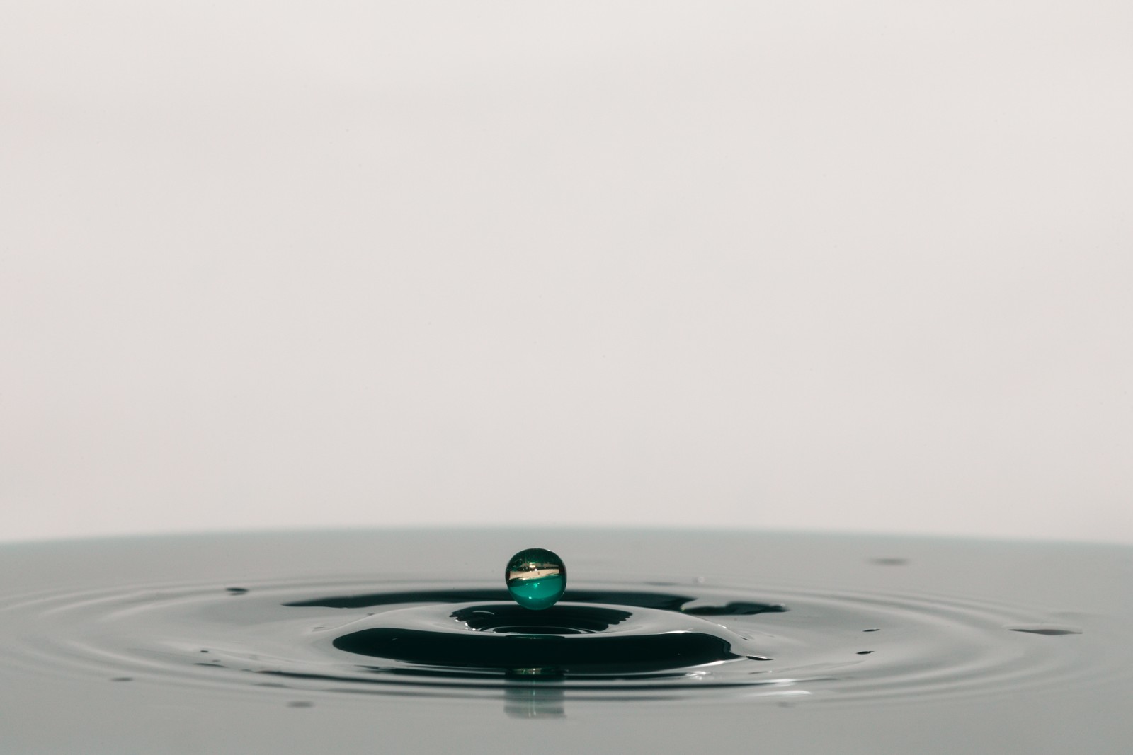 A close up of a drop of water with a green droplet (water, liquid, drop, green, water resources)