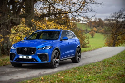 2021 Ягуар F-Pace SVR в ярком синем цвете на живописной загородной дороге.