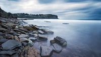 Serene Coastal Promontory with Rocky Shoreline Under a Dramatic Sky