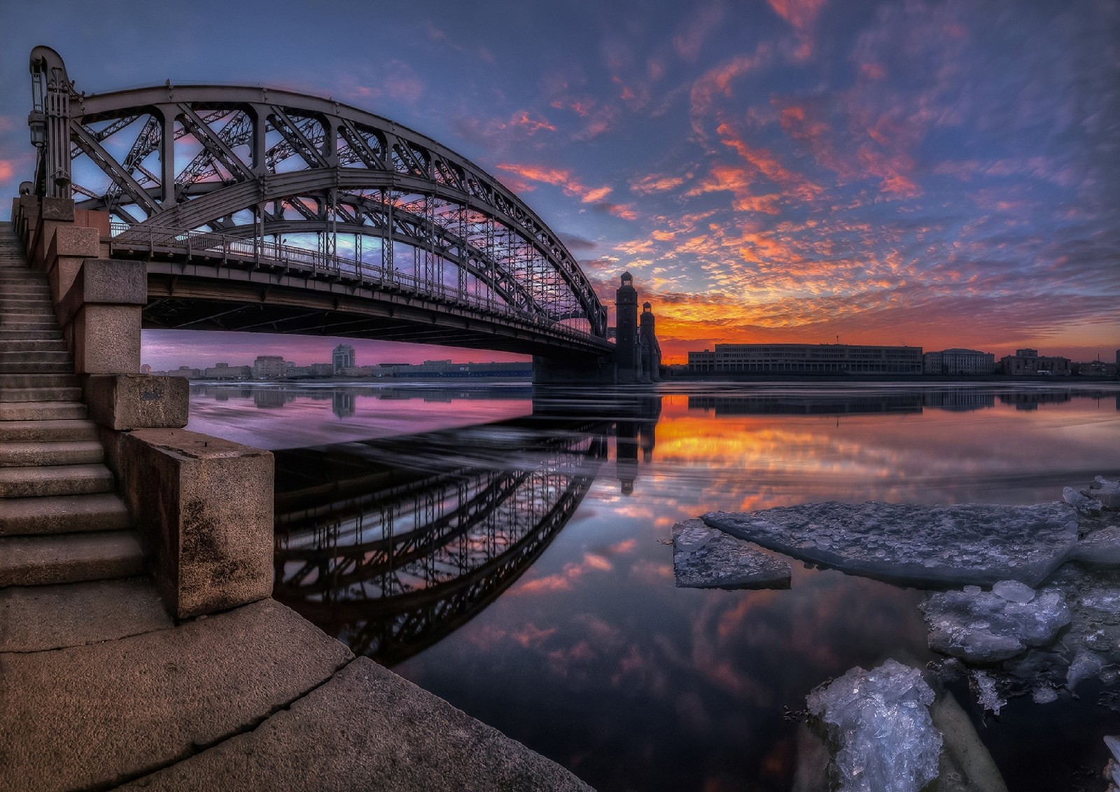 Une vue d'un pont sur un plan d'eau avec de la glace flottant sur l'eau (réflexion, coucher de soleil, paysage urbain, eau, pont)