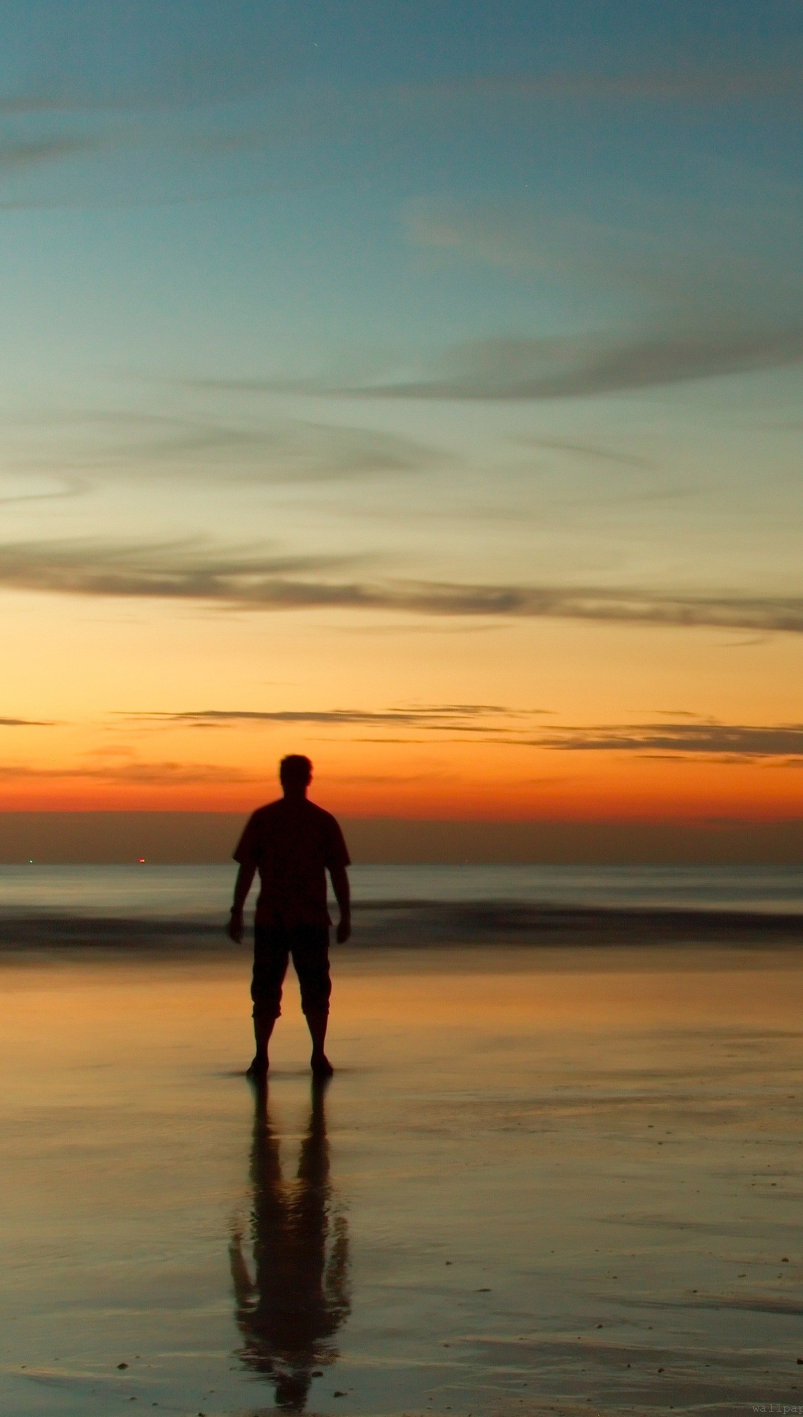 Un homme se tient sur la plage au coucher du soleil avec une planche de surf (seul, coucher de soleil)