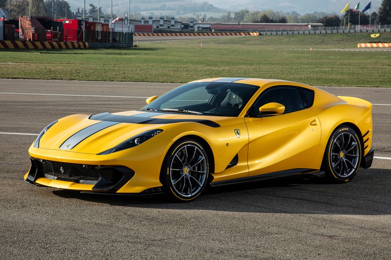 Желтый спортивный автомобиль ferrari едет по трассе на фоне зеленого поля (ferrari 812 competizione, 5k, 2021, машины, обои 4k)