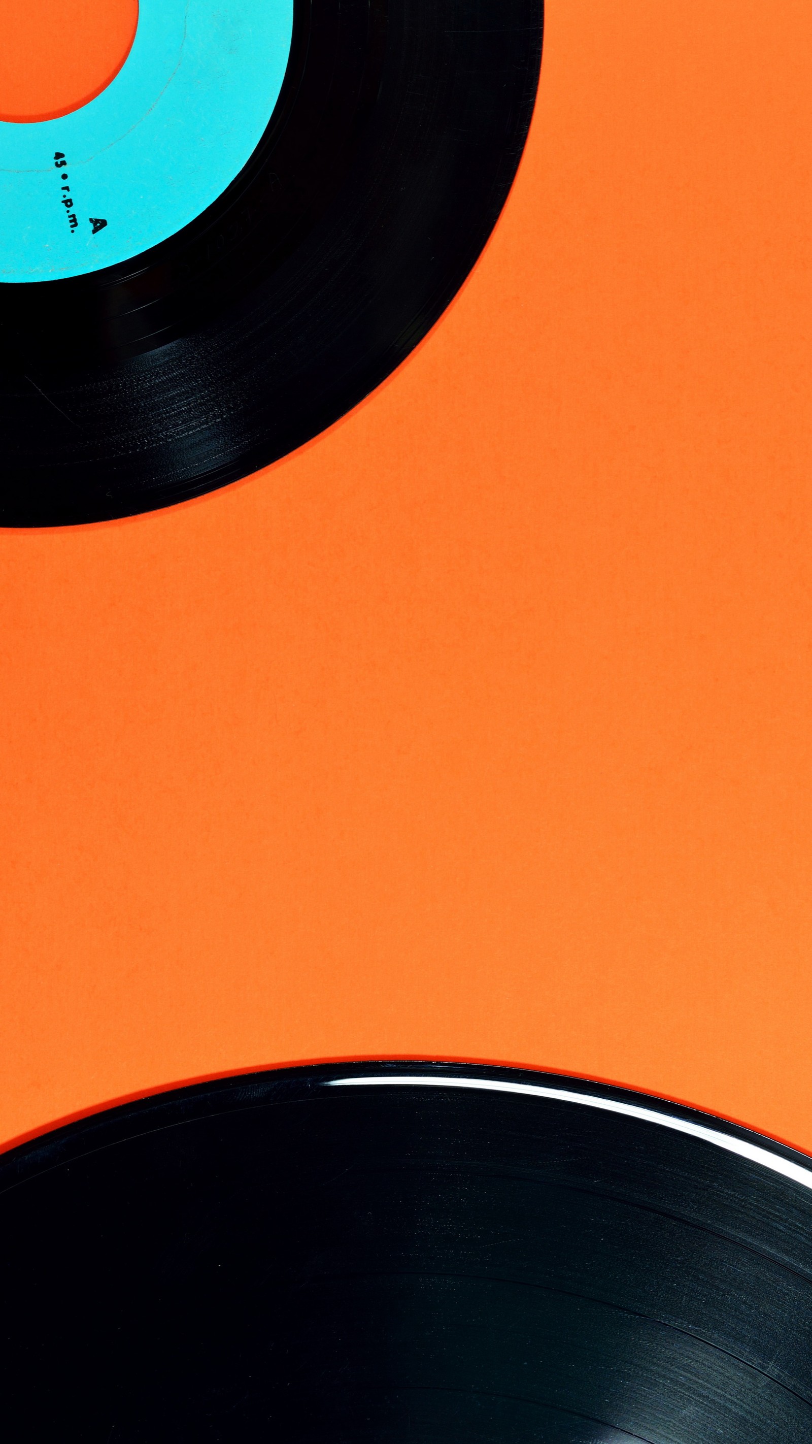 Il y a deux disques noirs et bleus sur une surface orange (orange, texte, lumière, ambre, art)