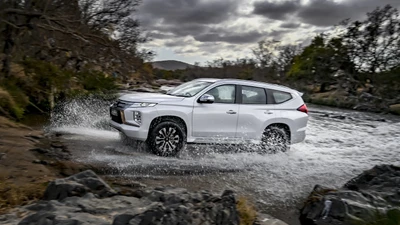 Mitsubishi SUV, der durch Wasser mit dynamischer Reifenleistung navigiert