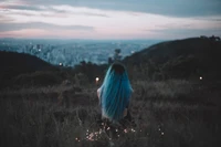 Chica con cabello azul mirando una ciudad en la hora dorada